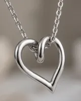 Set de joyería compuesto por collar con dije de corazón y aros tipo caravanas a juego, ambos con diseño minimalista de corazón abierto en acero.
