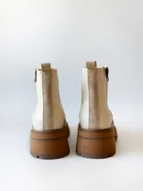 Bota corta de cuero vacuno con textura granulada, color crudo. Presenta cierre lateral metálico, suela track de goma en tono suela y tirador trasero.