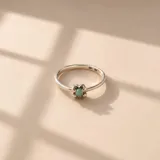 Anillo fino de plata 925 con un diseño de flor en el centro que engarza una pequeña piedra redonda de color verde.