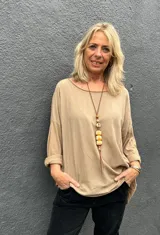 Blusa de corte holgado y diseño minimalista en color camel, con cuello redondo amplio y mangas tres cuartos con dobladillo.