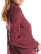 Campera bordó de modal con cuello solapa, cierre frontal con botones metálicos y bolsillos laterales. Presenta mangas largas con detalles labrados en los antebrazos y puños ajustados.