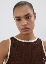 Top Tomi de tejido de punto marrón con diseño sin mangas y cuello redondo, decorado con detalles florales blancos bordados en el borde inferior.