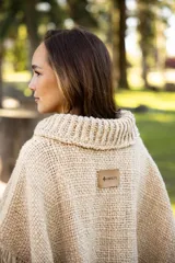 Poncho de lana merino color negro, con cuello alto, diseño amplio y terminaciones con flecos en todo el borde.