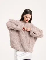 Buzo tejido a mano con lana, color rosa con motas de colores. Diseño oversized, largo entre la cintura y la cadera, con detalle de trenzas en las mangas.