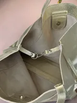 Bolso tipo tote Chabas confeccionado en cuero genuino color plateado, con un bolsillo frontal texturizado en tonos metalizados y doble asa superior para el hombro.