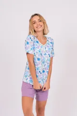 Pijama de dos piezas, compuesto por una remera de manga corta con botones y estampado de flores en tonos celeste, azul y lila, y un short lila con cintura elástica.