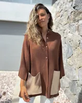 Saco tejido de punto en color marrón chocolate, con corte holgado y mangas anchas. Presenta cierre frontal con botones y dos bolsillos delanteros grandes en material metalizado color champán.