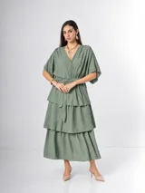 Vestido midi de crepé color marrón, con escote en V cruzado, mangas cortas amplias y falda escalonada con volados. Incluye lazo ajustable en la cintura.