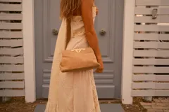 Mini cartera tipo sobre color arena con textura de reptil, cierre metálico dorado y cadena fina dorada para llevar al hombro.