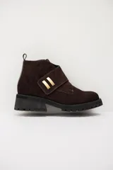Bota baja de gamuza color chocolate, con suela track negra y detalle de tira cruzada con apliques metálicos dorados.