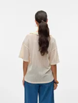 Remera oversize con cuello tipo polo y mangas cortas con hombros caídos, color crema.