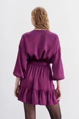 Vestido corto de estilo cruzado, color negro, con mangas largas abullonadas, puños elásticos y volado en el ruedo. Presenta un diseño de jacquard con corazones y cierre frontal con botones metálicos.