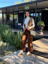 Cartera tipo bandolera de cuero color crudo, con diseño rectangular, solapa frontal con detalle de costura decorativa en el borde y correa ajustable.