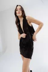 Chaleco negro de estilo boho, confeccionado en semigamuza con detalles de tejido de punto en el frente y la espalda. Presenta un diseño sin mangas con flecos en el ruedo, aportando movimiento y textura a la prenda.