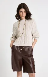 Sweater de punto beige con diseño de trenzas verticales, cuello redondo acanalado, mangas largas con puños ajustados y dobladillo acanalado.