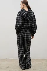 Pantalón de corte amplio y tiro medio-alto, confeccionado en tejido liviano con estampado a cuadros. Presenta cintura elastizada con lazo regulable y bolsillos laterales.