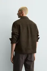 Sobrecamisa de corte relajado confeccionada en tejido de estructura irregular con lana. Presenta cuello solapa, cierre frontal con botones, mangas largas con puños abotonados y bolsillos frontales con solapa en el pecho.