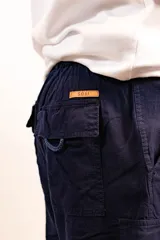 Bermuda color beige de lino tipo cargo, con bolsillos laterales y dos traseros. Cuenta con elástico en la parte de atrás, cierre y botón en el frente.