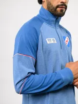 Buzo deportivo de medio cierre marca Umbro del Club Nacional de Football. Presenta un diseño en tonos azul y gris jaspeado, con cuello alto, mangas largas y detalles de costuras en contraste. Incluye el escudo del club y logo de la marca en el pecho.