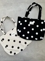 Tote bag de algodón color negro con estampado de lunares blancos. Cuenta con doble asa de hombro y etiqueta frontal con el logo de la marca.