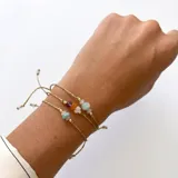Conjunto de tres pulseras de hilo encerado dorado con nudo corredizo, decoradas con cuentas de piedras naturales como amazonita, cuarzo rosa, ámbar, amatista y piedra luna.