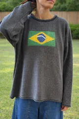 Sweater oversize gris oscuro con bandera de Brasil bordada en el frente. Tiene cuello redondo, hombros caídos y un calce suelto.