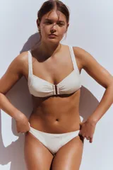 Bombacha de bikini tipo vedetina color beige, con textura arrugada y lazos laterales ajustables.