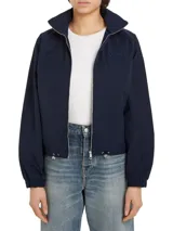 Cortavientos azul marino con cuello alto, cierre de cremallera, dos bolsillos con botones, detalles distintivos de Tommy Hilfiger y logo gráfico bordado en el pecho.