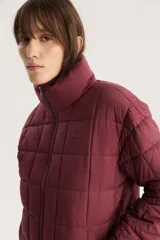 Campera puffer acolchada color borgoña con cuello alto y cierre frontal.