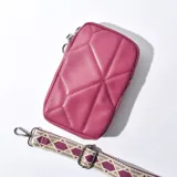Porta celular fucsia con diseño acolchado y correa de tela estampada con motivos geométricos.