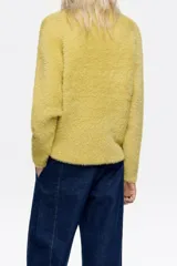 Jersey de textura suave y peluda, con cuello subido y manga larga, diseñado con un corte cómodo y envolvente.