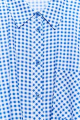 Camisa corta de cuello solapa y manga larga, con estampado de cuadros vichy en color bordó y blanco. Presenta un bolsillo delantero de parche, bajo abullonado con elástico interior y cierre frontal con botones.