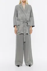 Chaqueta gris de lyocell con corte recto, escote con solapas, manga larga recta y cierre frontal con cinturón de tejido. Tiene bolsillos plastrón redondeados en el delantero.