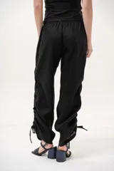 Pantalón negro de tiro medio con cintura elástica ajustable con cordón y detalles de fruncido con tiras en los laterales de las piernas.