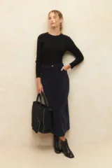 Maxifalda de pana color azul marino, de tiro alto con cierre y botón metálico. Presenta diseño de cinco bolsillos y abertura trasera.