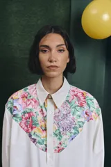 Camisa de corte oversize con mangas largas y puños abotonados. Presenta un diseño bicolor con cuerpo blanco y un canesú delantero con estampado floral multicolor.