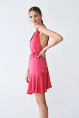 Vestido midi fucsia de tejido sastrero fino y liso con leve brillo, escote en V, tiras para ajustar en la cintura, volado asimétrico en el ruedo y espalda descubierta.