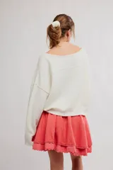 Minifalda color coral, de tela liviana con dos capas de volados, cintura elastizada con cordón ajustable y borde festoneado con puntilla.