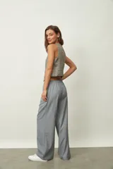 Chaleco corto de mujer con estampado de cuadros en tonos beige, gris y naranja, escote en V y cierre frontal con botones.