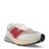 Championes urbanos New Balance modelo U370, con diseño retro en tonos gris, beige y rojo. Presentan una combinación de malla y gamuza en el exterior, con el logo 'N' característico en color rojo intenso y una suela de doble capa en tonos crema y gris.