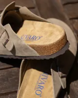 Zuecos cerrados de cuero gamuzado color beige, con tira ajustable y hebilla metálica. Presentan plantilla anatómica de corcho y látex.