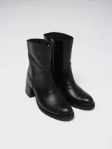 Botas de caña baja en cuero color marrón oscuro, con taco cuadrado y punta redondeada. Presentan un diseño tipo western con estribo desmontable que incluye una hebilla metálica decorativa.