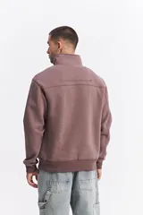 Buzo de algodón con medio cierre frontal y cuello alto. Presenta puños y ruedo acanalados, con un pequeño logo bordado en el pecho.