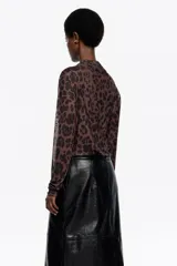 Camiseta de manga larga confeccionada en tejido de tul semitransparente con estampado animal print abstracto. Presenta cuello redondo, corte ajustado y detalles de frunces laterales que aportan textura y movimiento a la prenda.