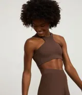 Top deportivo de mujer con diseño halter, confeccionado en microfibra de poliamida y elastano. Cuenta con copas integradas y breteles anchos en la espalda para mayor soporte.