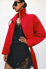 Chaqueta corta roja ZARA Woman Collection con mezcla de algodón, cuello alto, manga larga, bolsillos delanteros y cinturón ajustable con lazada en el mismo tejido. Cuenta con cierre frontal con botones ocultos por solapa.