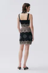 Vestido corto negro de tejido de punto con técnica jacquard, escote cuadrado, tirantes anchos y falda con estampado de árboles plateados.