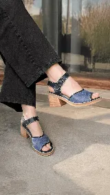 Sandalias de cuero combinadas en azul y negro, con diseño de textura croco en la capellada, costuras en contraste y taco ancho de madera. Poseen tira al tobillo con hebilla metálica regulable.