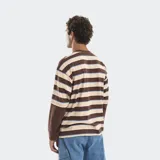 Remera de manga larga con diseño de rayas horizontales en tonos marrón, beige y azul. Presenta un corte boxy holgado y un efecto de superposición en las mangas con puños en color marrón sólido. Incluye un logo bordado en el pecho y en la manga derecha.