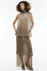 Pantalón de punto fino color beige, de corte recto y holgado, con cintura elástica y una falda pareo superpuesta con nudo lateral.